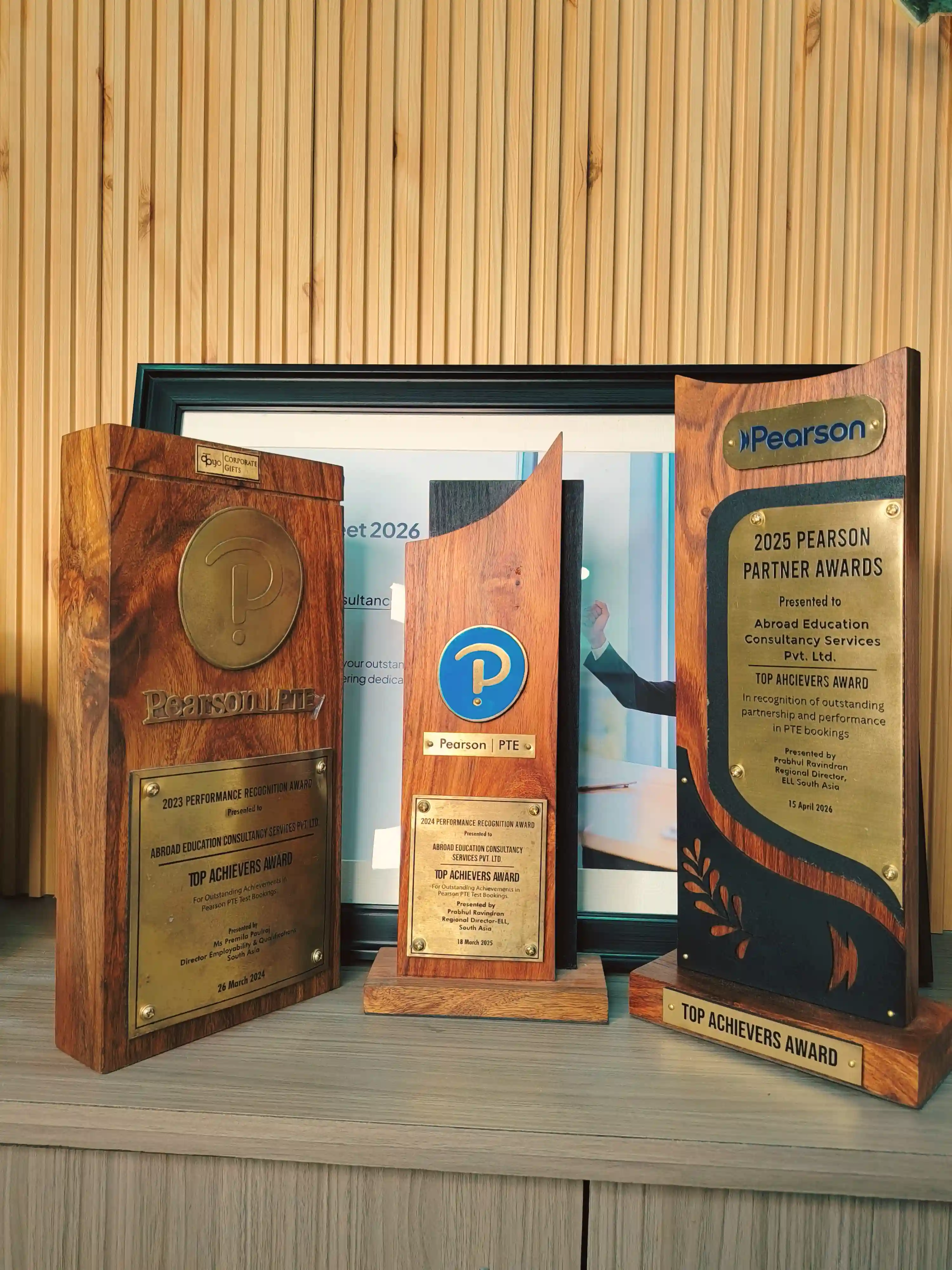 Pearson PTE Top Achievers trophies — 2023, 2024 and 2025